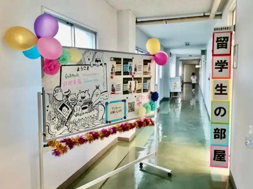 入口のイメージ、廊下にホワイトボードで留学生の紹介などが掲示されています。画像は去年のもので、変更される可能性があります。